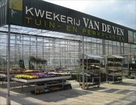 Ingang van de kwekerij-winkel met rekken vol perkplanten